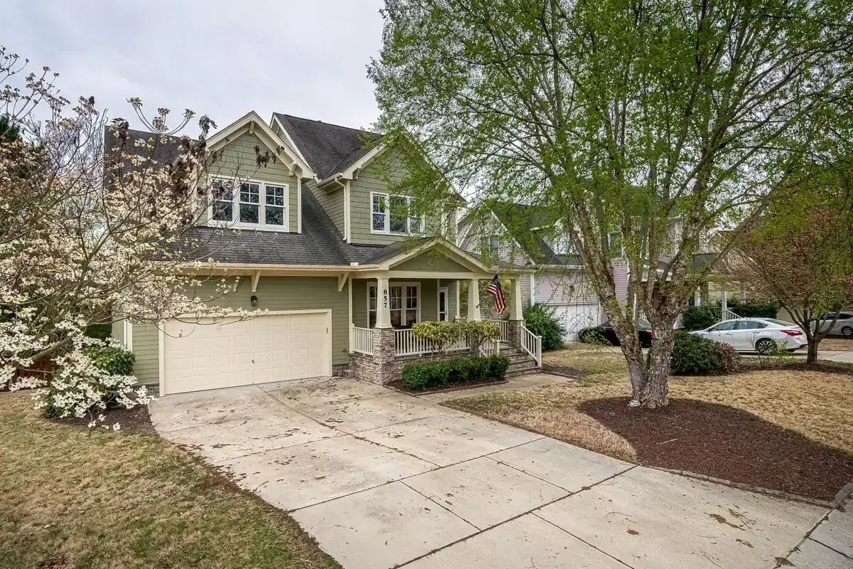 Suburban house and driveway shaded by a large established front-yard tree